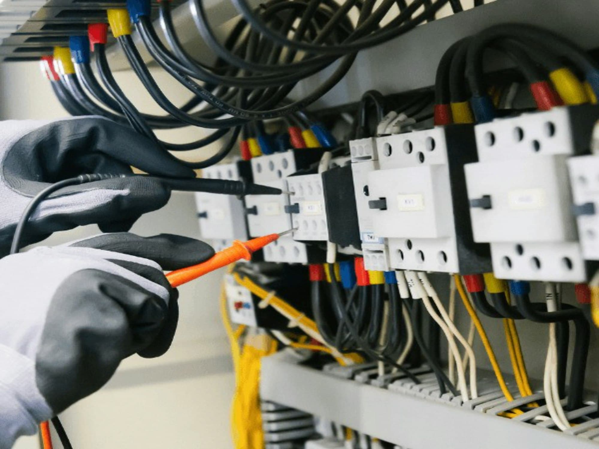 Mains gantées vérifiant un tableau électrique
